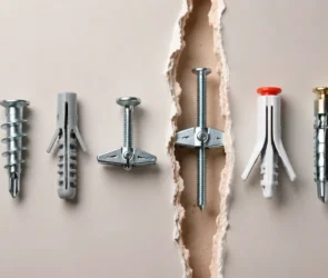 Blog featured image about drywall anchor types and weight ratings, displaying a variety of drywall wall anchors laid out in a row, including plastic self-drilling anchors, expansion anchors, and a toggle bolt inside a torn drywall panel gap