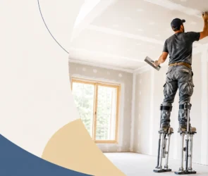 A professional drywall contractor standing on aluminum stilts while taping and mudding a ceiling in a newly constructed room