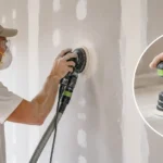 Blog featured image guide on sanding drywall with an orbital sander, showing a worker wearing safety glasses and a respirator mask using a handheld random orbital sander with a vacuum hose attachment on a mudded wall seam, with a close-up inset of the sanding pad.