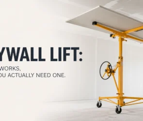 A professional yellow drywall lift holding a large sheet of gypsum board perfectly flat against a high ceiling, demonstrating how the mechanical crank and locking wheels allow for safe, solo installation.