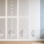 Blog featured image guide on drywall finish levels 0 to 5 explained, showing a side-by-side six-panel progressive wall layout from level 0 bare boards, through intermediate taped, mudded, and skim coated phases, up to a premium level 5 smooth painted blue accent wall, with detailed circular corner insets for each step.